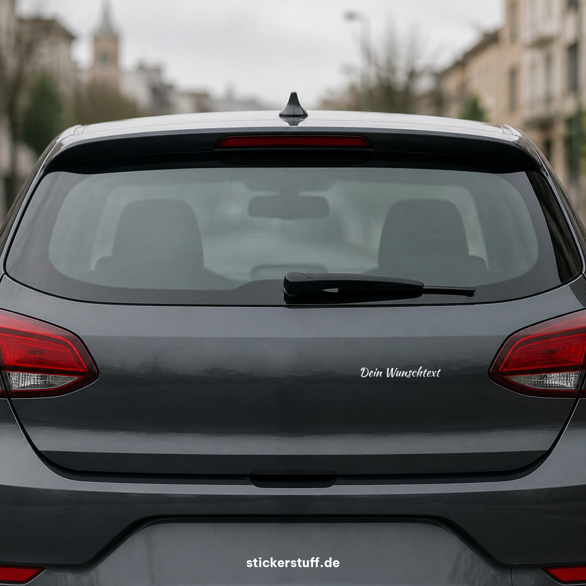 Wunschtext Plottsticker auf der Heckklappe eines dunkelgrauen Autos – Beispiel in realistischer Größe